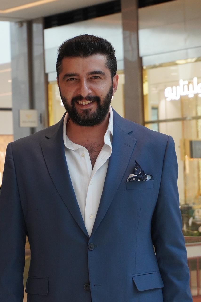 Burak Sarıkaya standing in a suit inside a mall